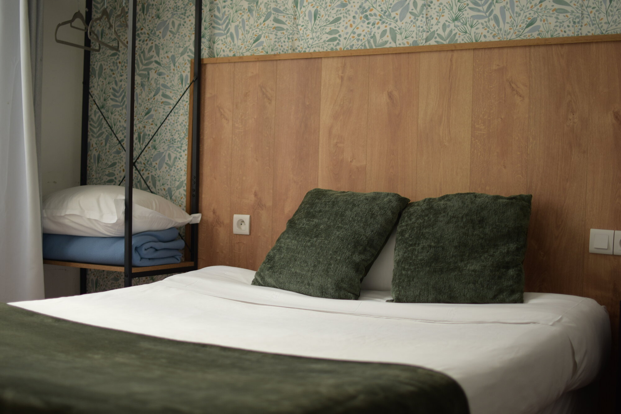 Studio Double avec coussins verts et papier peint fleuri